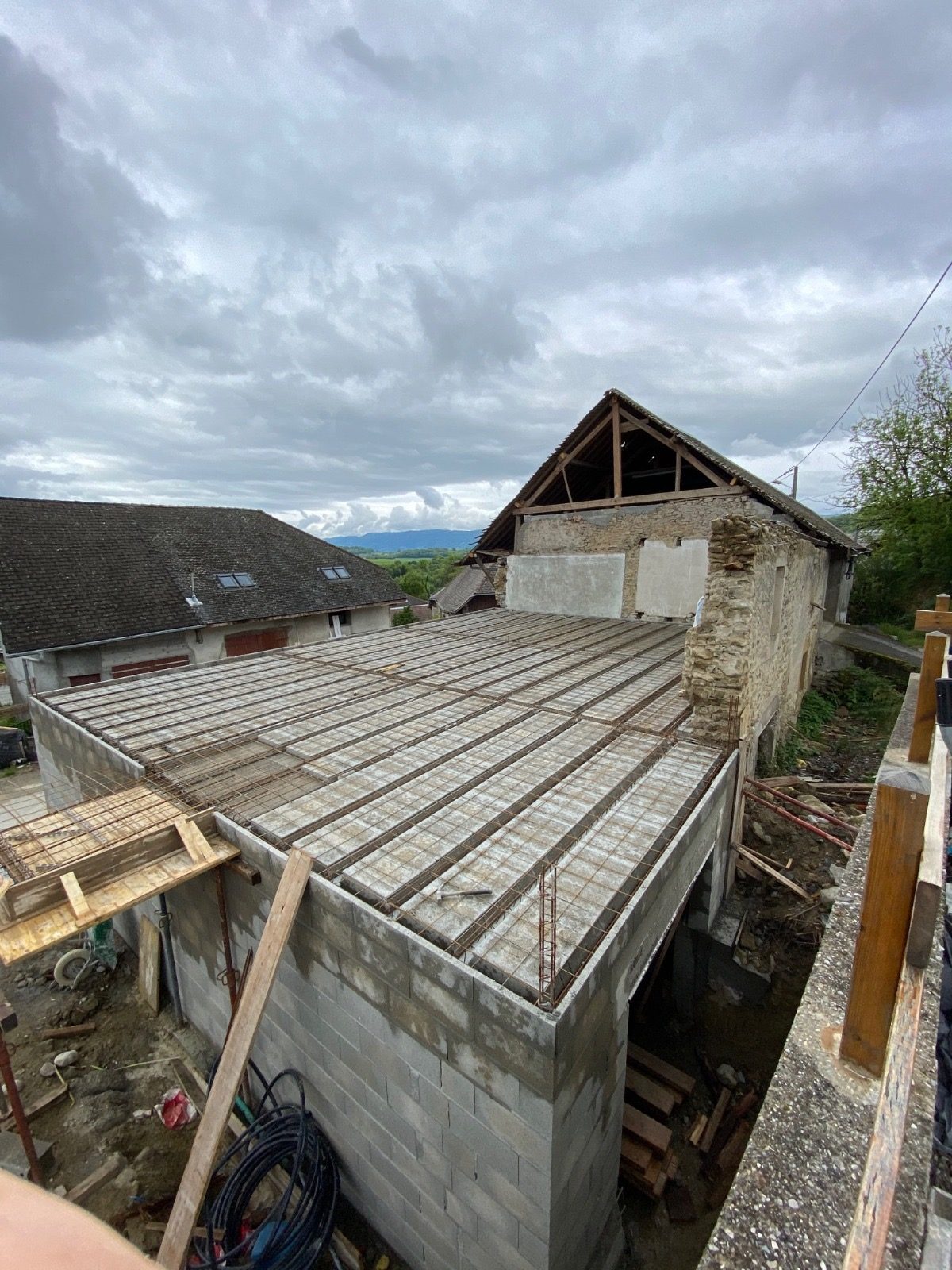 Dalle béton armée sur extension, bâtiment en pierre à rénover en arrière-plan